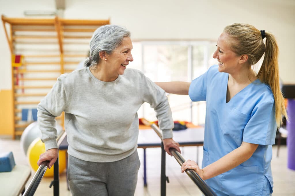 Physiotherapist assisting older woman in movement therapy